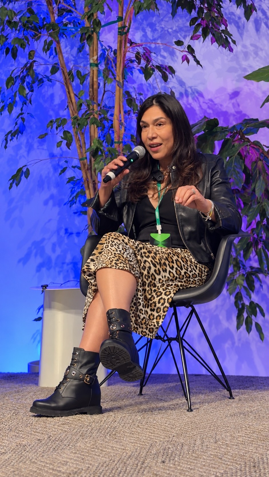 Monica Monique speaking on stage at a panel, holding a microphone