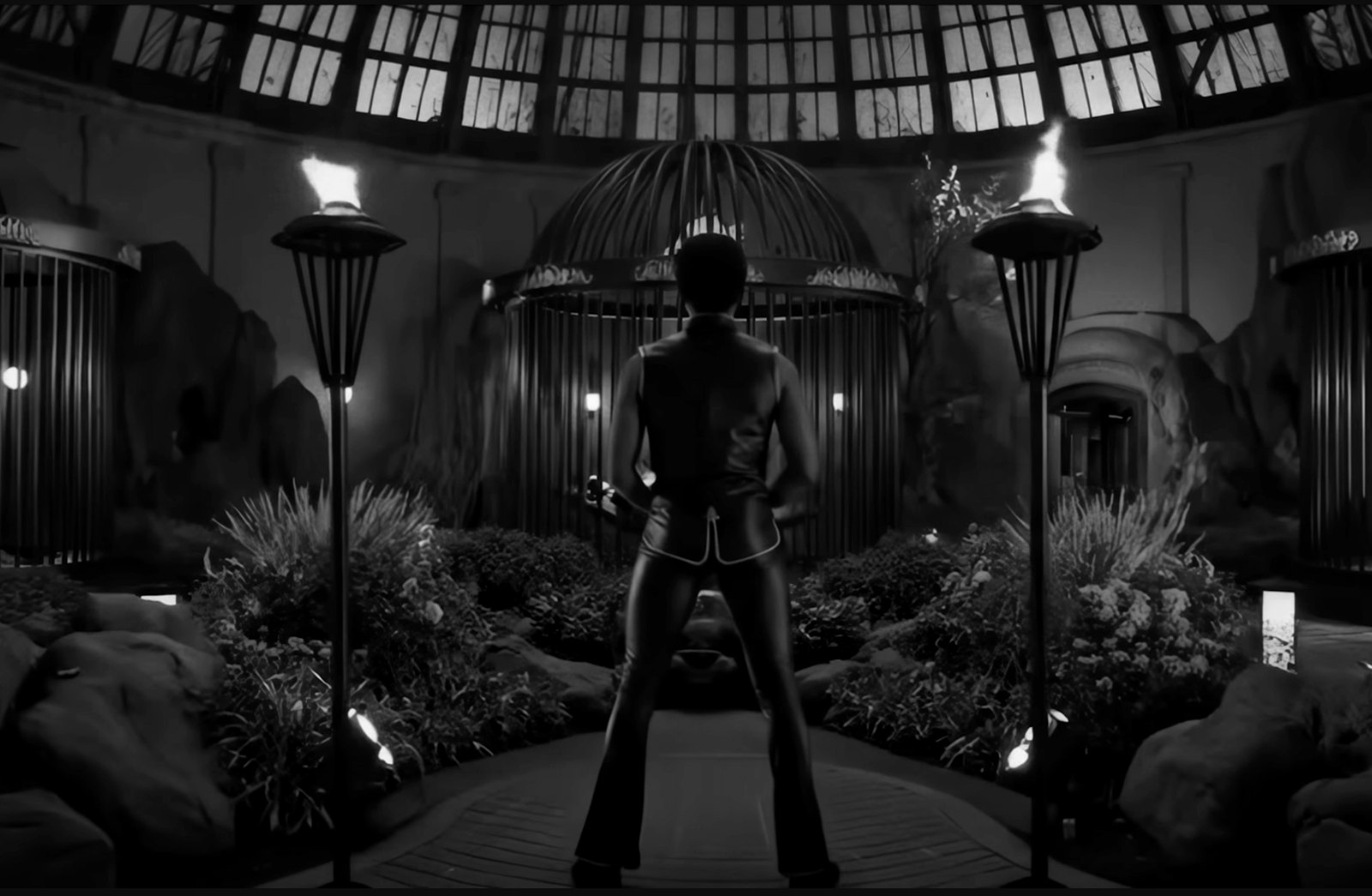 Still from Wu-Tang Clan “Mandingo”: a figure in leather facing a domed conservatory with cages and torches